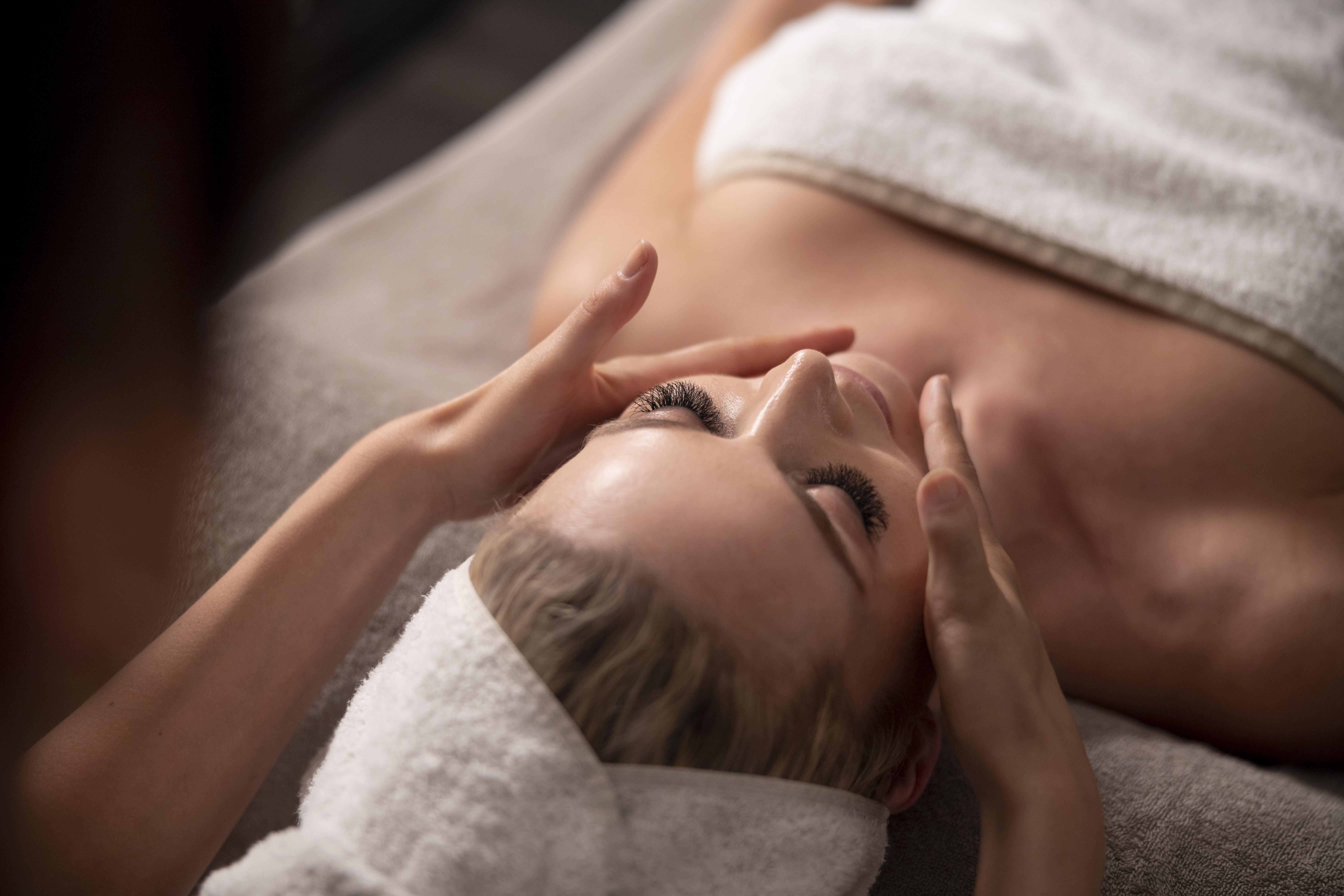 young-woman-massaging-her-client-s-face maquillage-permanent-cils